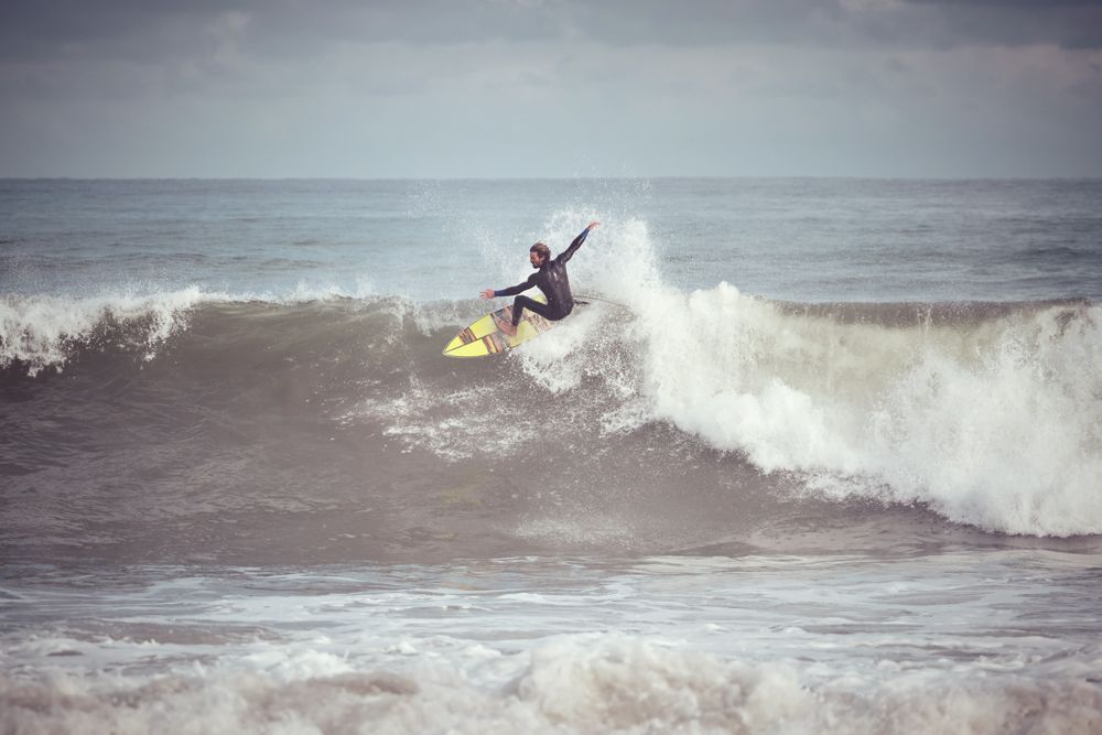 Man surfer on surfboard catching wave on ocean