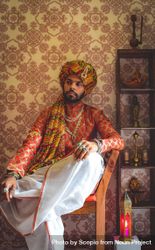 Man wearing turban and traditional Indian outfit sitting on chair indoor 4dmYEb