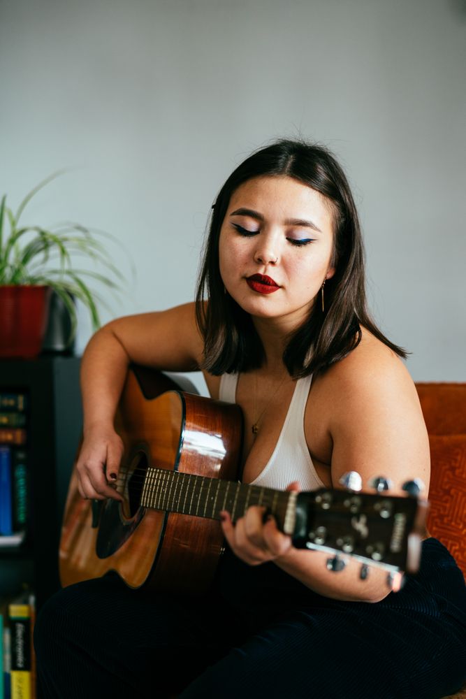 Young woman playing guitar inside house