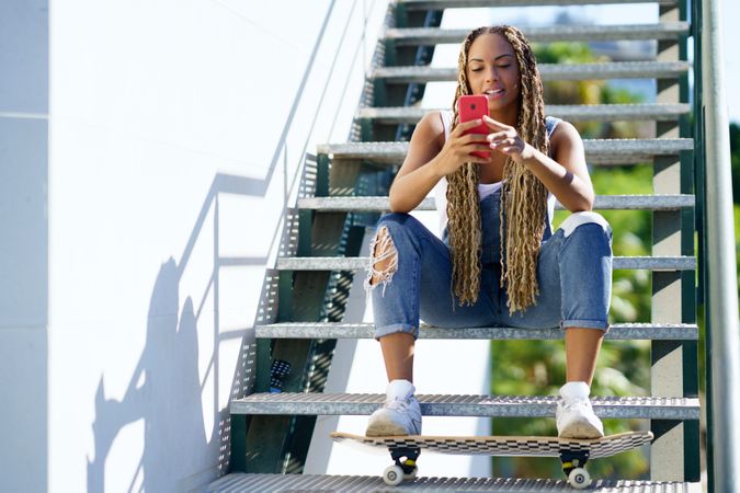 Female skater checking phone on stairs, copy space