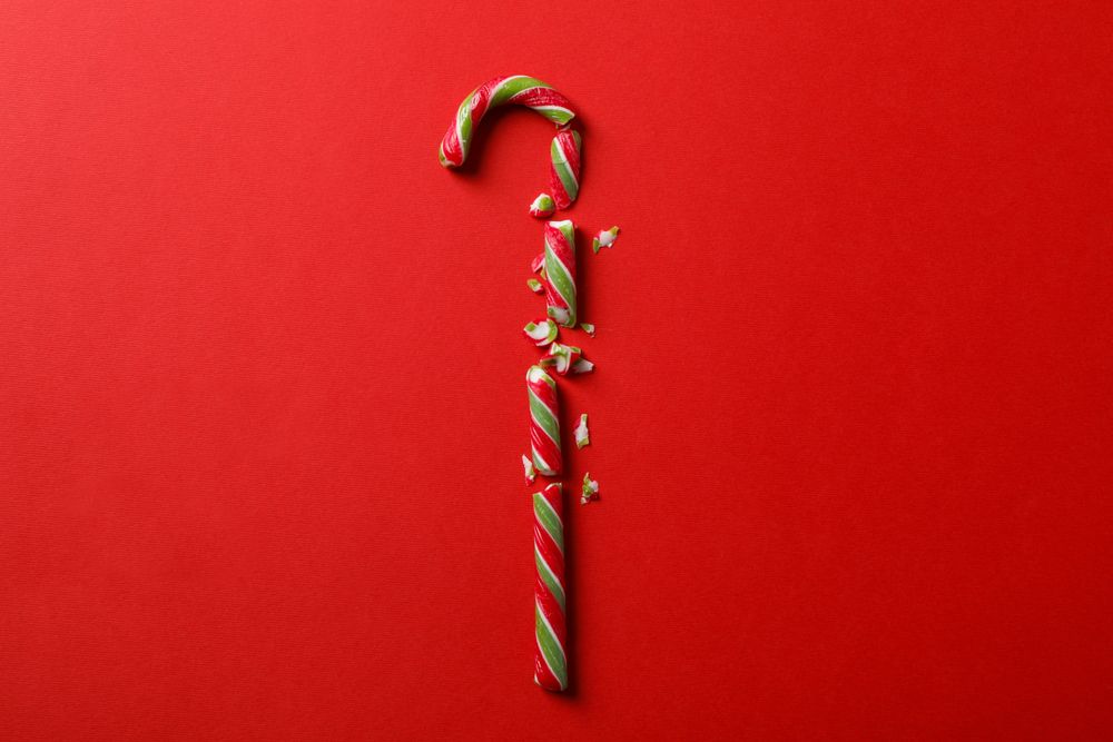 Broken candy cane on red background, space for text