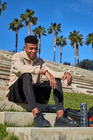 Smiling Hispanic sportsman sitting on stairs