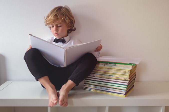 Focused boy in suit reading book