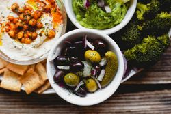 Tasty hummus and sauces decorated with bright cut vegetables on table