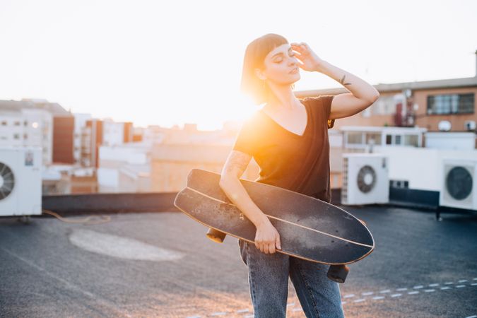Woman holding skateboard on rooftop