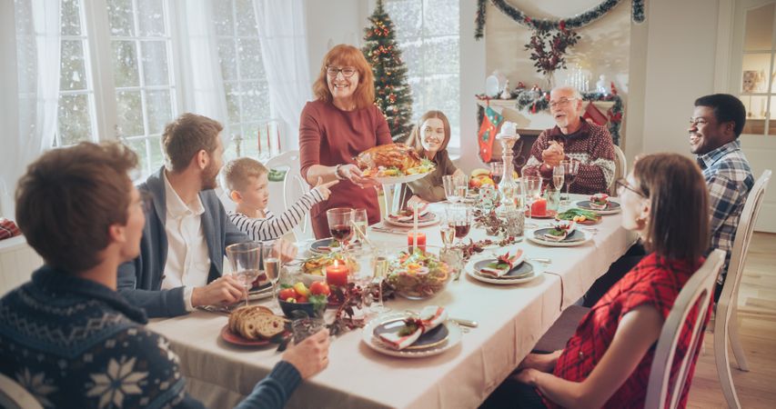 Diverse Group of Relatives and Friends Sitting Together Behind a Dining Table with Tasty Meals and Festive Decorations.