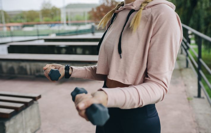Woman training with dumbbells outdoors