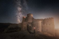 Man beside ruined fort under starry night sky