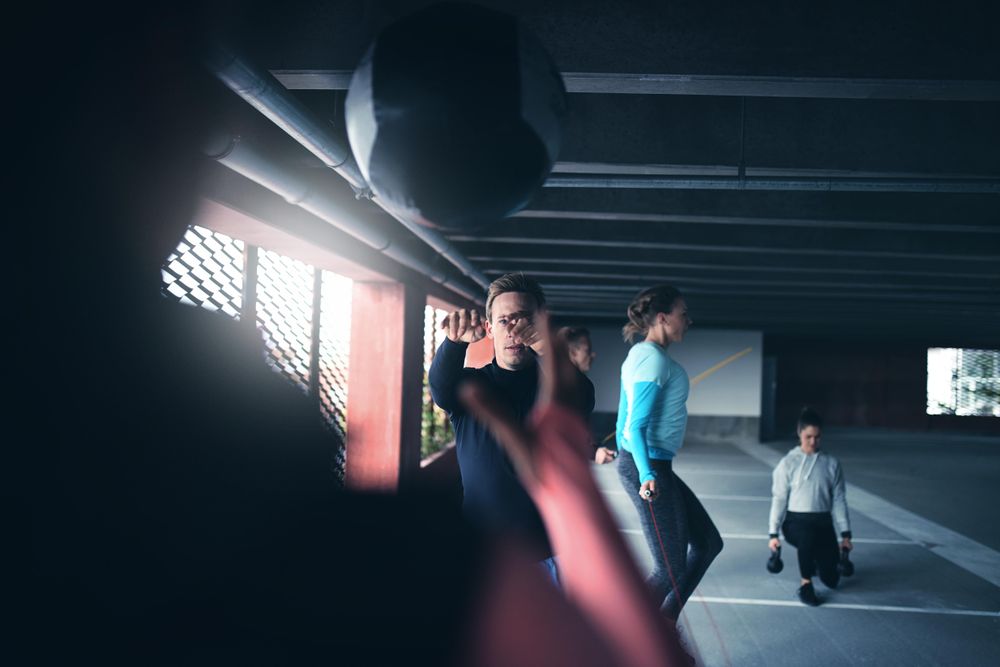 Two men throwing a medicine ball and women doing lunges and jumping rope
