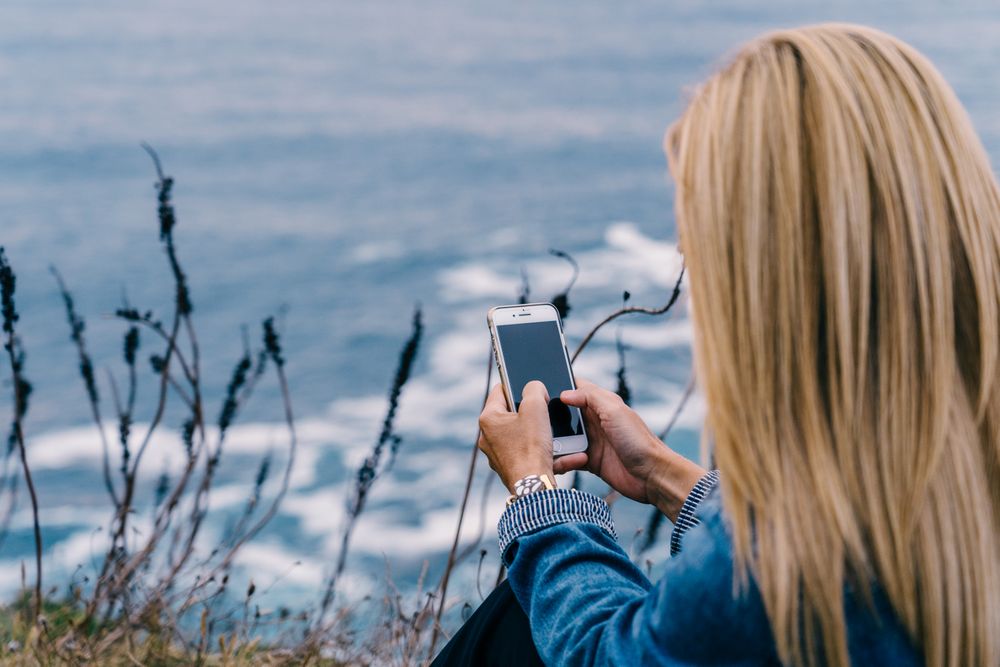 Female tourist taking shot of sea in twilight