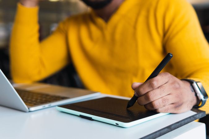Anonymous Black man working on laptop with tablet