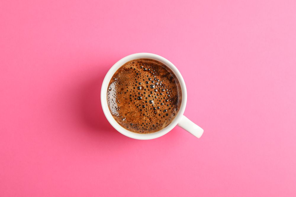 Cup of coffee on color background, space for text