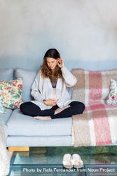 Pregnant woman relaxing at home sitting cross legged on sofa 5orWy0