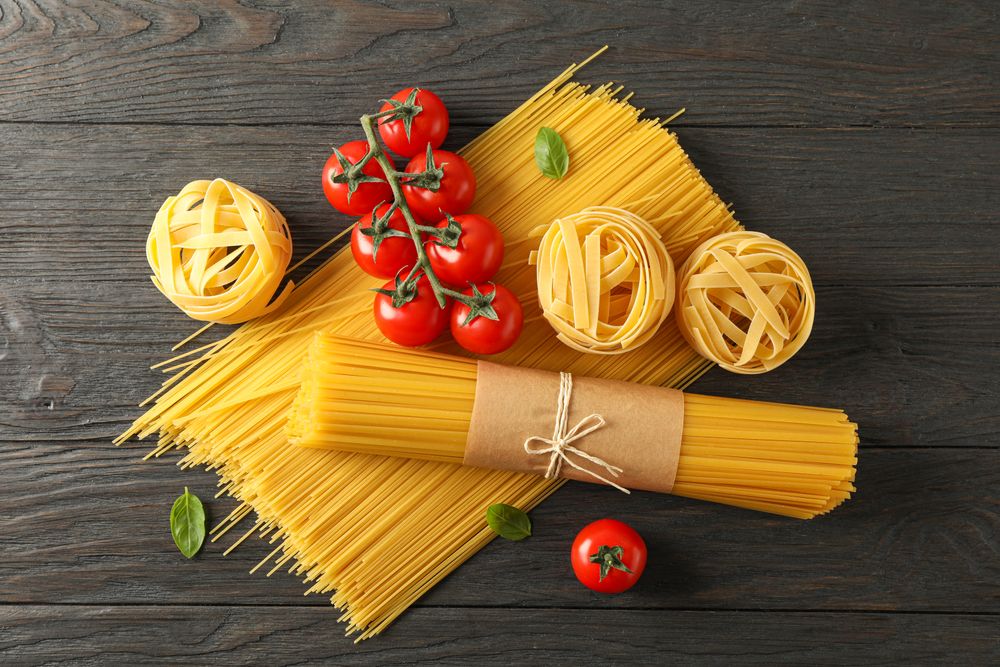 Composition with pasta, tomatoes and basil on wooden background, space for text and top view