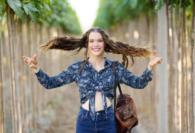 A Joyful and Cheerful Young Woman with Long Hair, Found in a Beautiful TreeLined Pathway