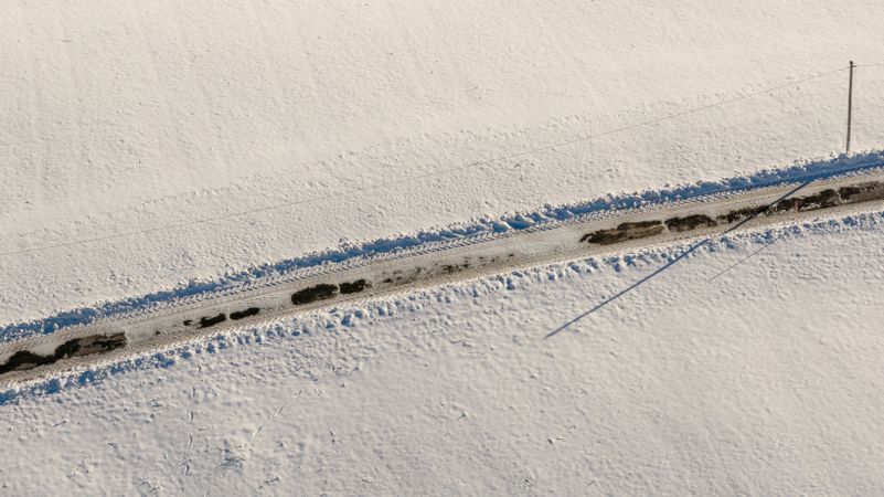 Road through deep snow in the German mountains, drone aerial view