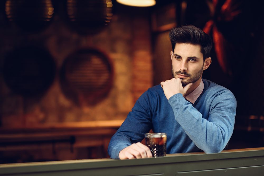 Man sitting in cafe window with cocktail