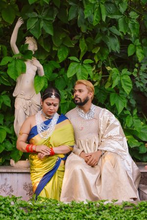 Indian man and woman sitting beside statue in a garden