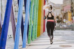 Woman with earphones running on street