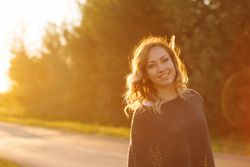 Smiling female standing on country road at dusk