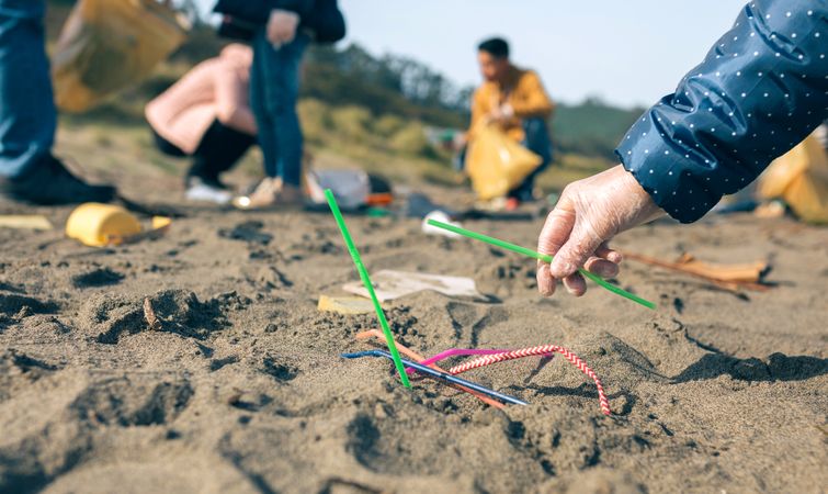 Woman picking up straws on the beach