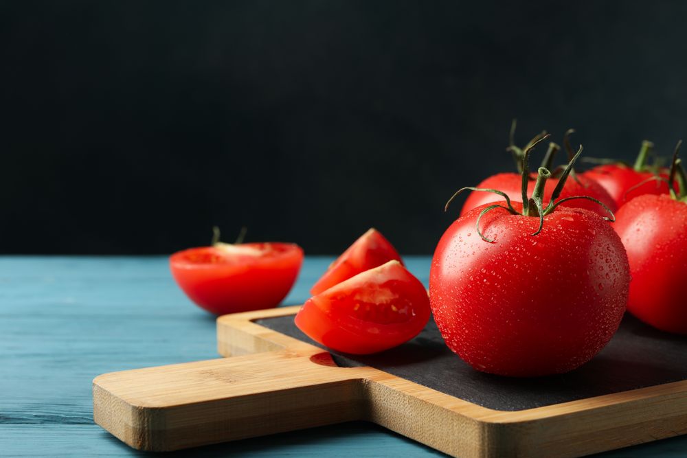 Fresh tomatoes on board on wooden table. Ripe vegetable