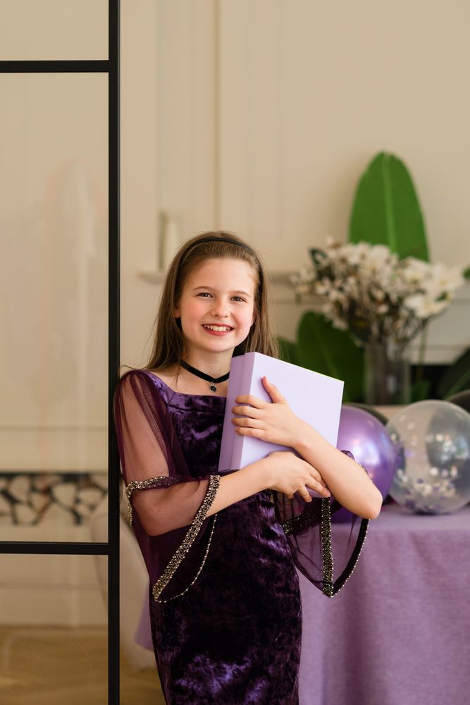 Smiling girl holding gift box at birthday party.