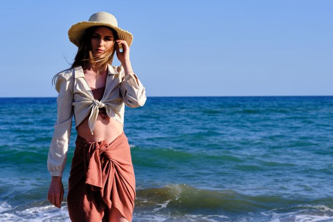 A fashion model with a hat at the beach before sunset