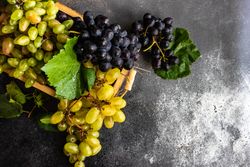 Box of delicious fresh green & red grapes with leaves on counter