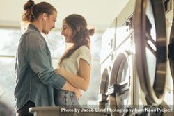 Intimate couple holding each other standing in a laundry room 5olj94