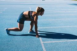 Young woman in starting position on a track field