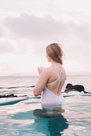 Woman sitting in pool near stones