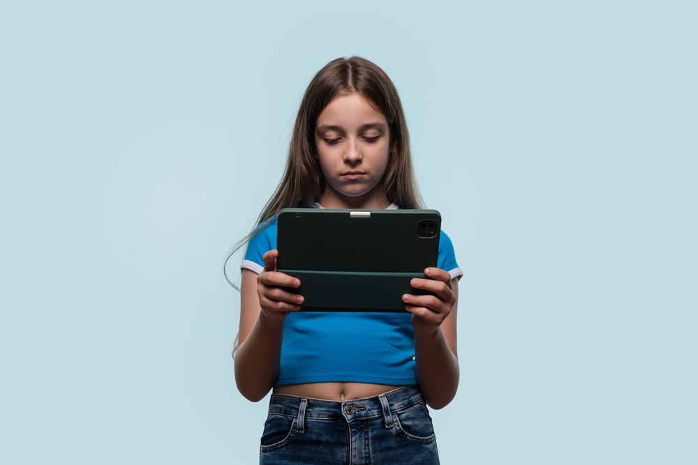 Girl looking focused and serious while using tablet