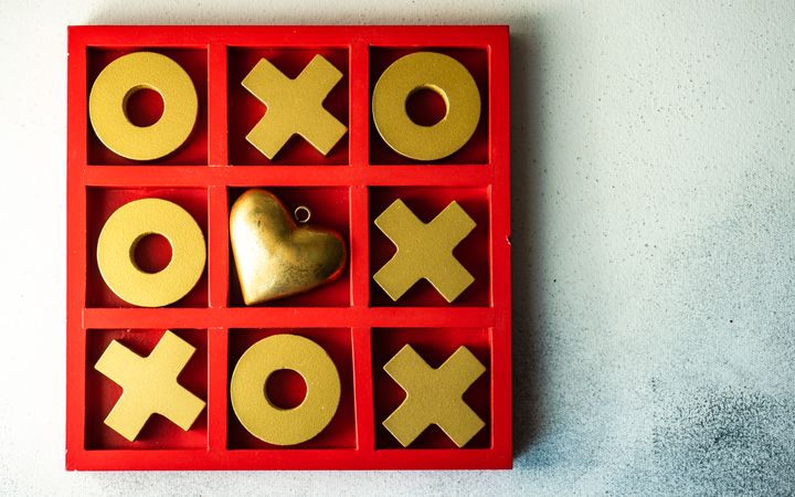 St. Valentine day card concept with gold heart in center of tic-tac-toe game