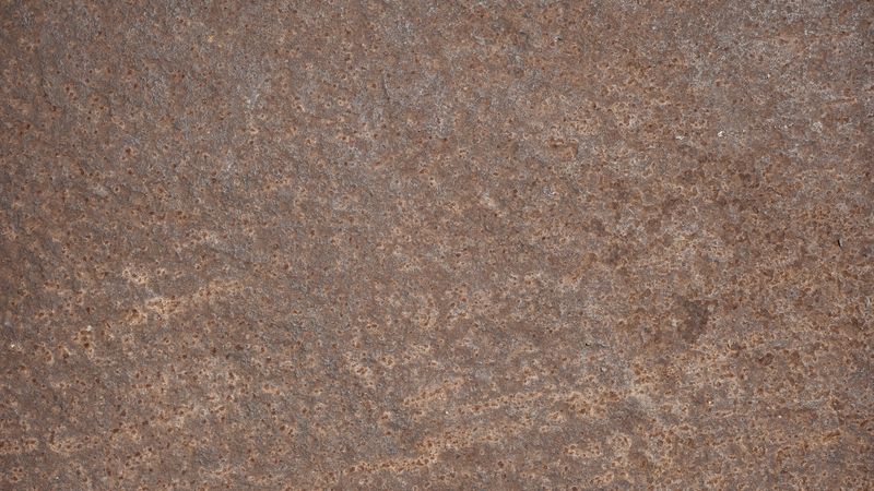 Corroded metal surface with small holes and aged rust texture