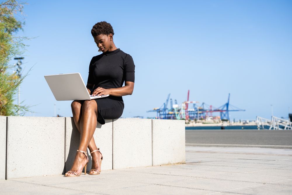 Serious female surfing laptop near modern building