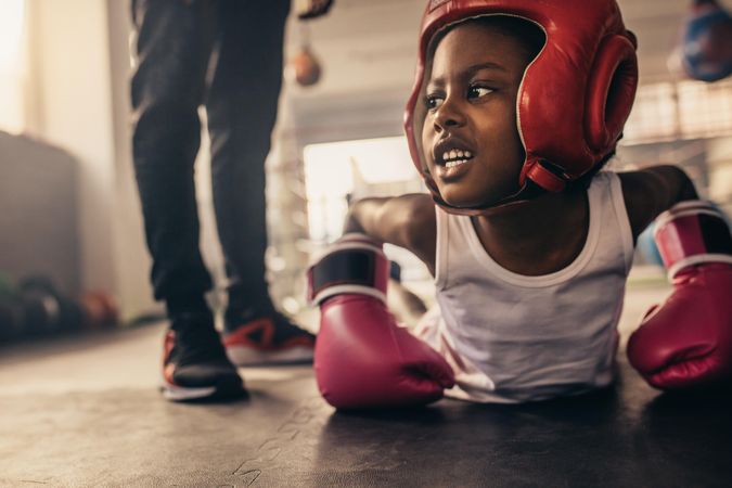 Girl wearing boxing gloves and headgear doing push ups