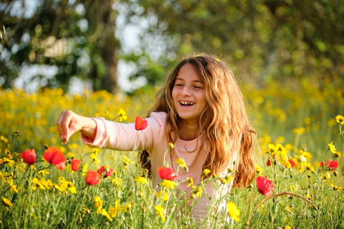 Happy girl playing with flowers in field