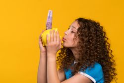 Girl kissing piggy bank, emphasizing importance of saving