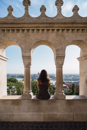 Woman sitting on columned marble fence