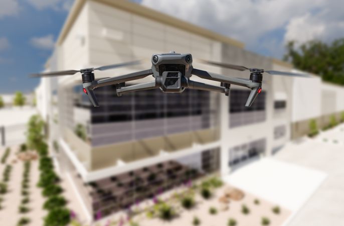 Unmanned Aircraft System Quadcopter Drone UAV In The Air Near Corporate Industrial Building