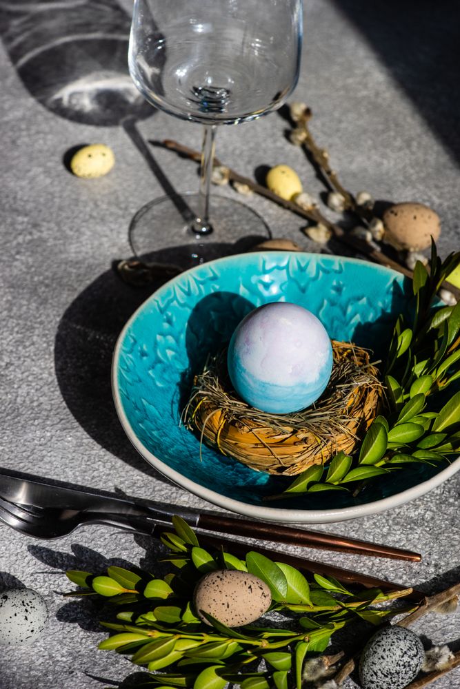 Easter table setting with teal bowl with decorative egg in nest