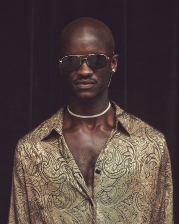 London, England, United Kingdom - September 18 2021: Black man in gold patterned shirt and choker