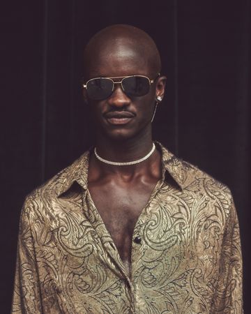 London, England, United Kingdom - September 18 2021: Black man in gold patterned shirt and choker