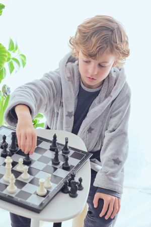 Focused preteen boy playing chess game on board