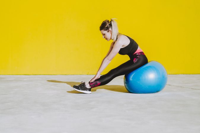 Woman stretching while sitting on ball