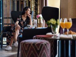 Trendy woman resting in armchair in cafe in hotel