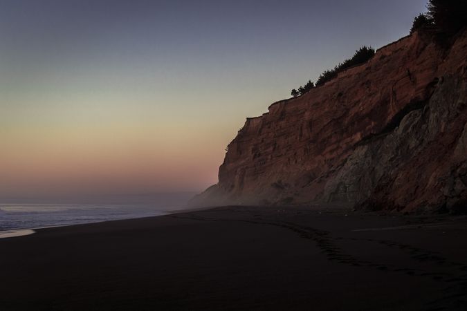 Side of cliffs on foggy Pacific Ocean beach