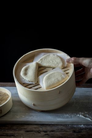 Cook preparing buns in bamboo steamer