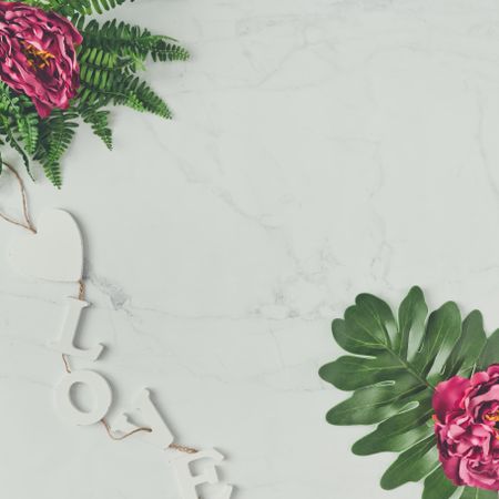 Pink flowers and leaves on marble background with the word “Love”